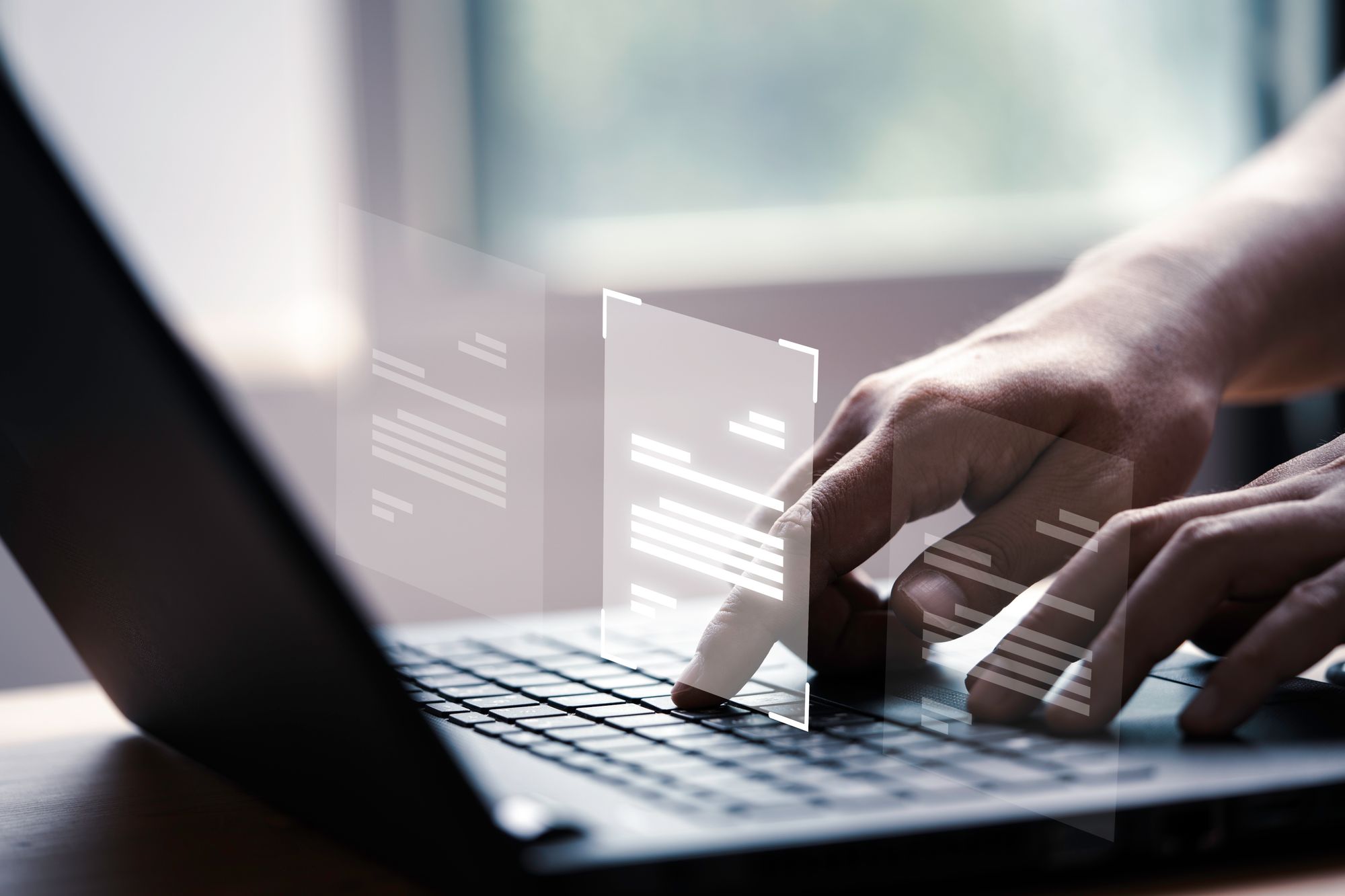 Hands using a laptop keyboard with digital, transparent documents hovering above the keyboard.